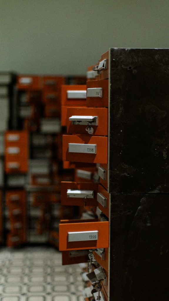 A row of open orange metal lockers in a dimly lit indoor hallway, creating a moody industrial atmosphere.
